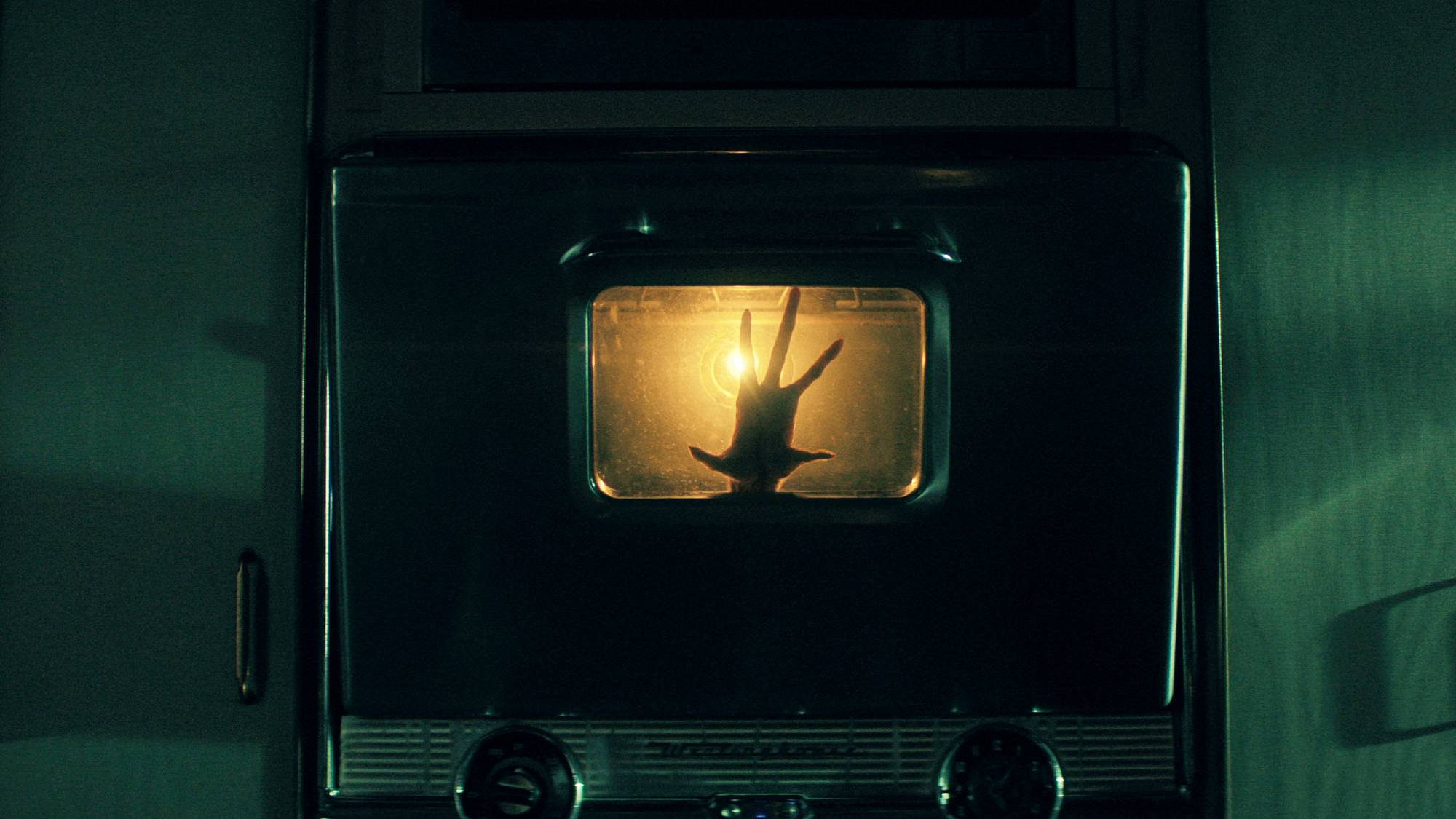 A scene of an alien hand appearing in the oven in "The Boroughs" on Netflix