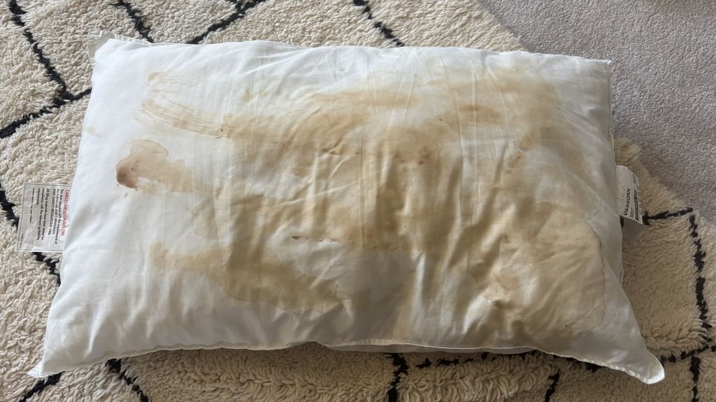 A stained pillow on the floor of a living room.