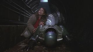 Still from the movie RoboCop 3 (1993). Here we see RoboCop face down in a sewer with his young sidekick trying to help him up.