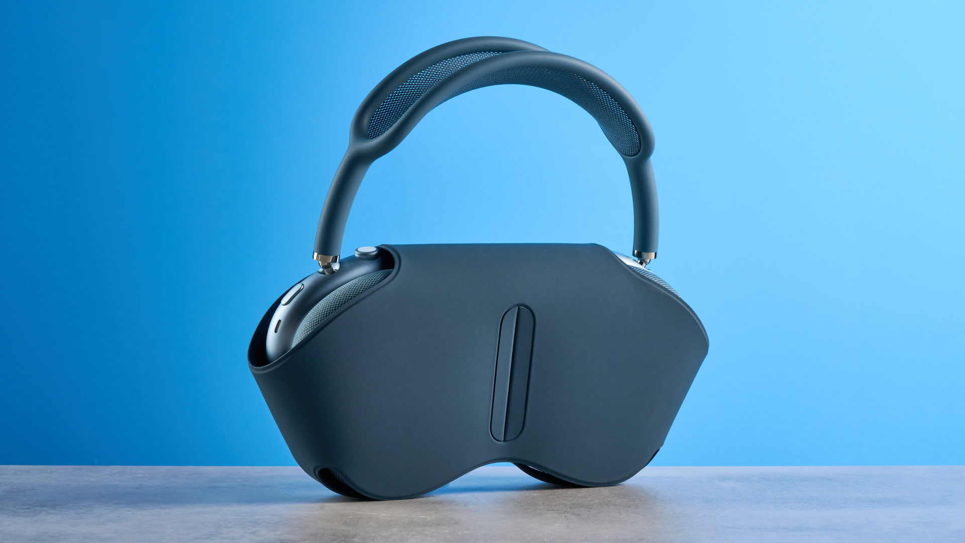 the apple airpods max 2 in blue photographed against a blue tom's guide background, showing the mesh headband, anodized aluminum ear cups, carry case, and controls