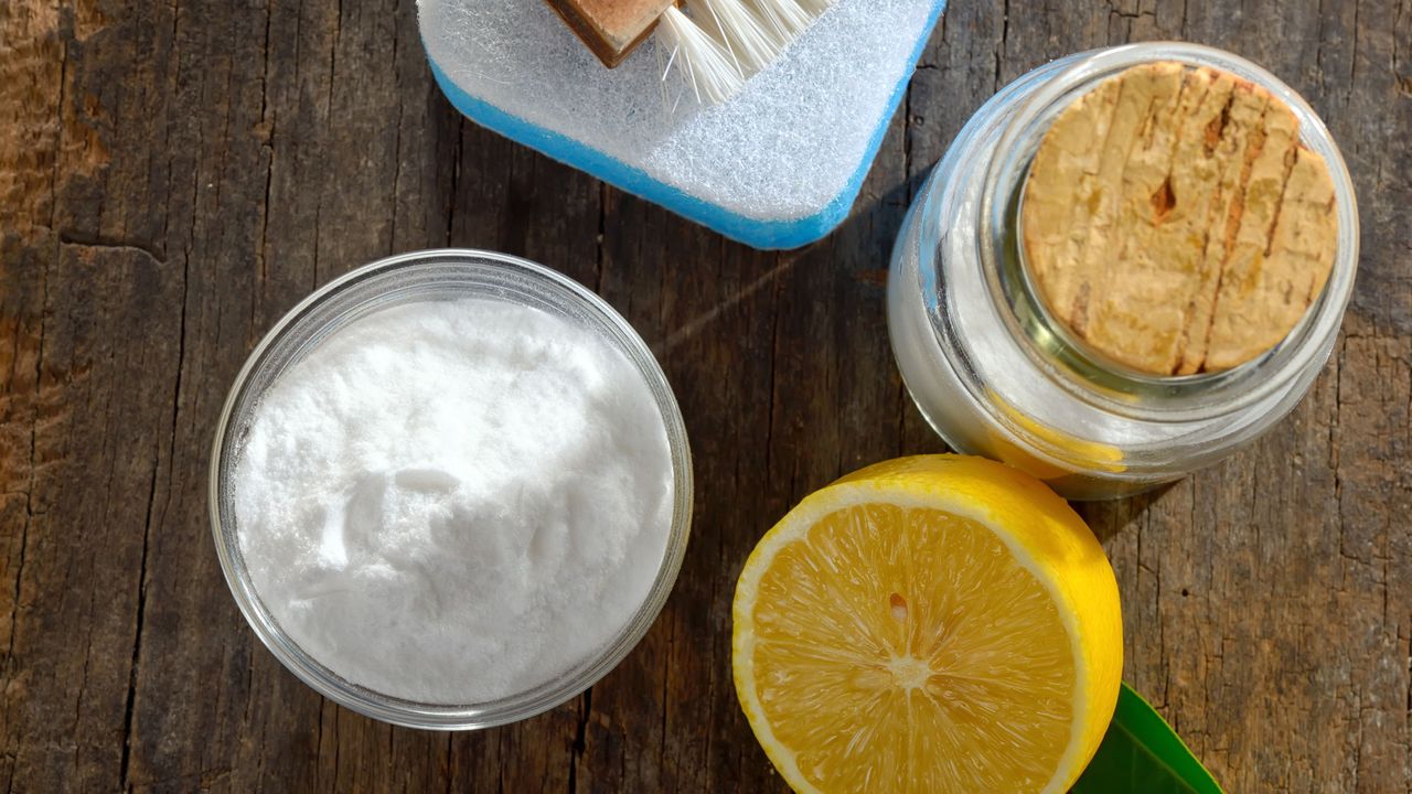 A selection of cleaning materials including bicarbonate of soda and fresh lemons cut in half