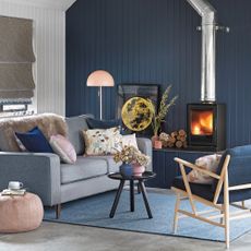 Living room with blue and white wall panelling, wood burning stove and grey sofa