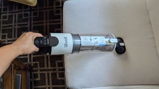 Levoit LVAC-200 cordless vacuum in handheld mode, being used to clean reviewer's sofa