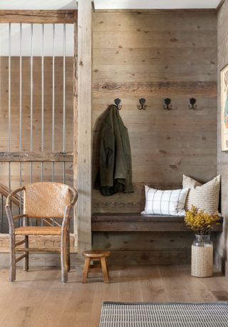 bench seat and coat hooks with wooden walls and vintage armchair and stool