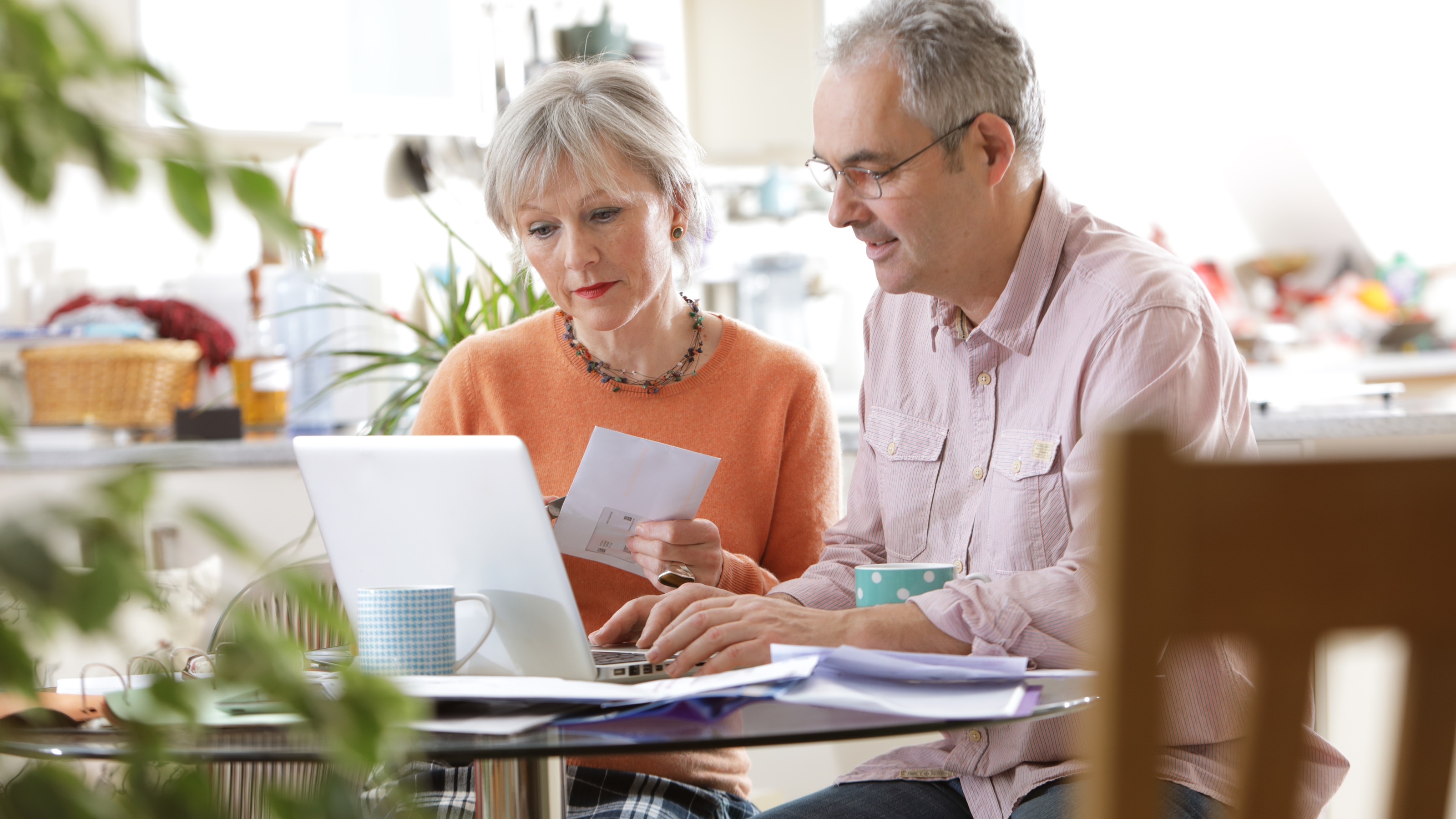 A couple work together on financial planning at their kitchen table.