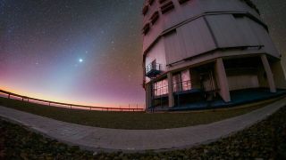 a starry, pinkish-purple dusk sky glows above a large telescope dome