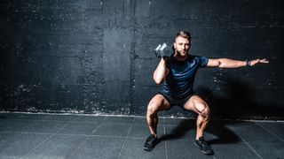 Man performing a single-arm dumbbell squat against a wall