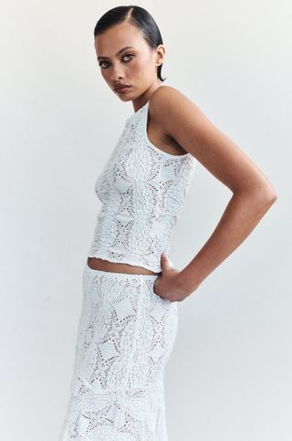 a model wears a sleeveless white lace top