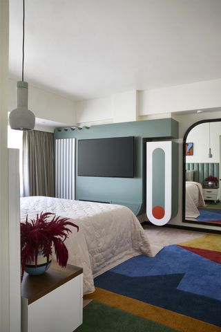 A bedroom with a TV unit painted in bright hues