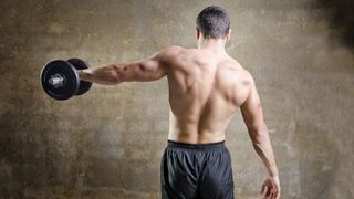 Man with back to camera performing single-arm dumbbell lateral raise left arm