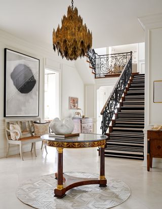 Entryway with statement chandelier and table in center.