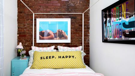 small bedroom in New York apartment with exposed brick wall and white four poster bed