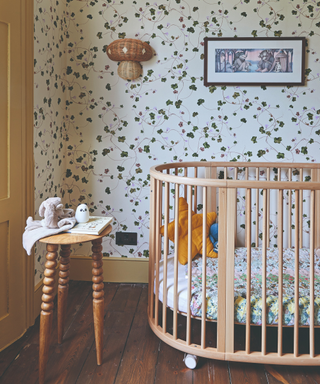 child's nursery with slatted cot and clover wallpaper and bobbin side table