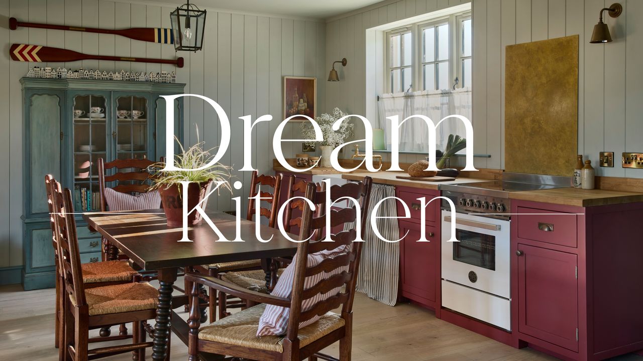 A Scottish coastal cottage kitchen with soft blue paneled walls, burgundy cabinets, a wooden kitchen table, and a dark blue antique cabinet