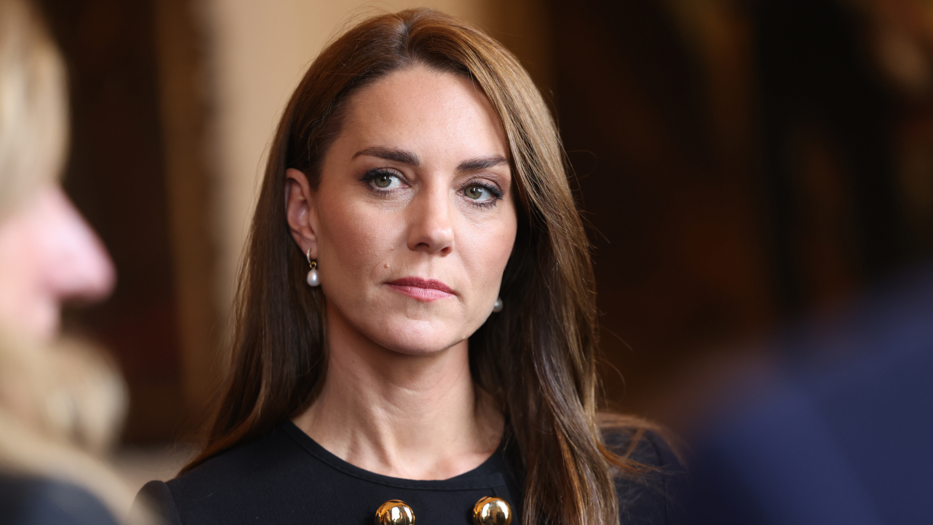 Kate Middleton has long brunette hair and wears a black outfit
