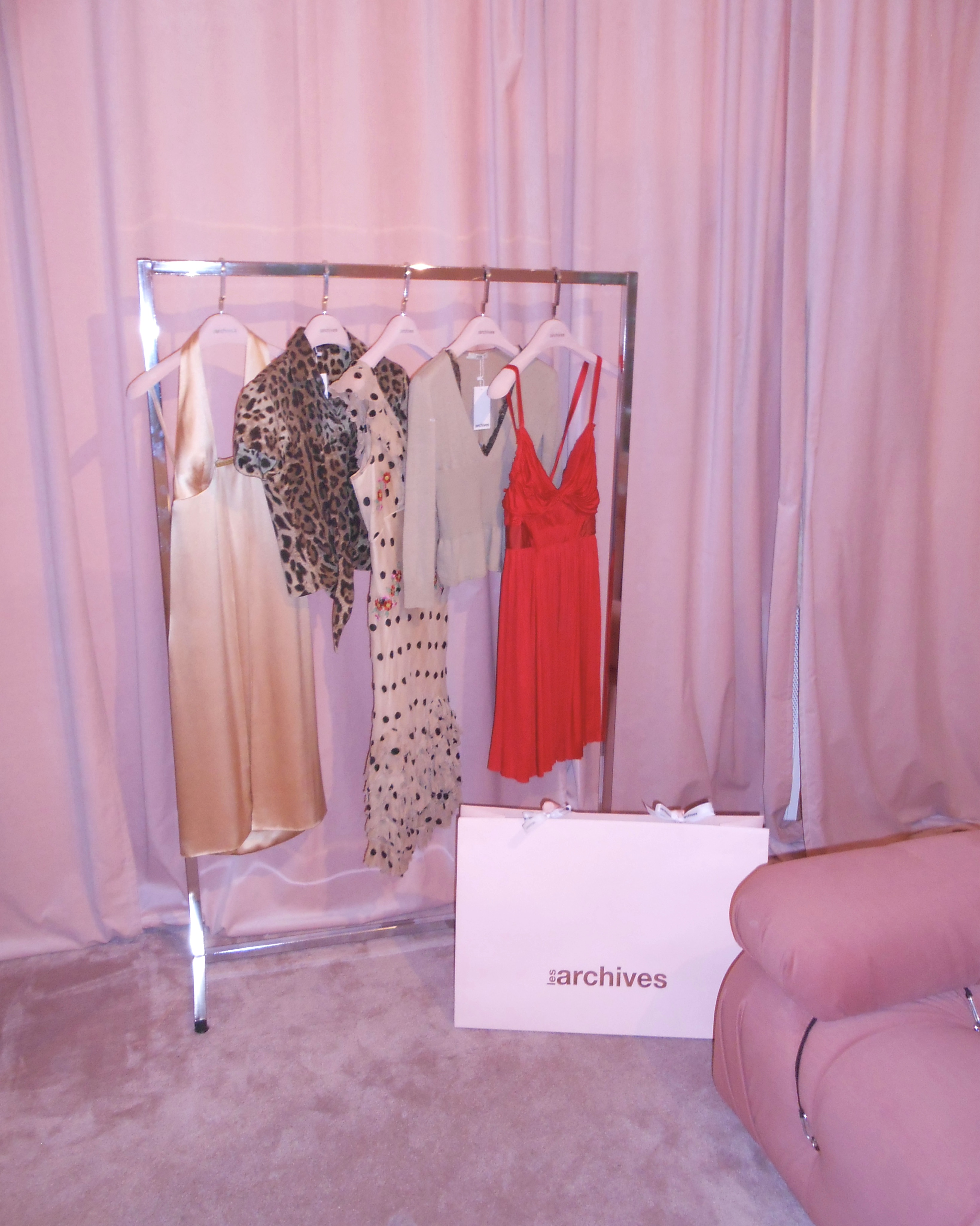 Clothing rack in front of a pink backdrop inside Les Archive Vintage, one of the best vintage stores in Paris.