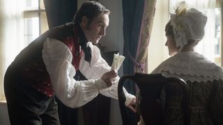 Captain Sutherland (Derek Riddell) in a white shirt and red waistcoat shows a letter to wife Elizabeth (Katherine Kelly) in a lacy bonnet in Gentleman Jack