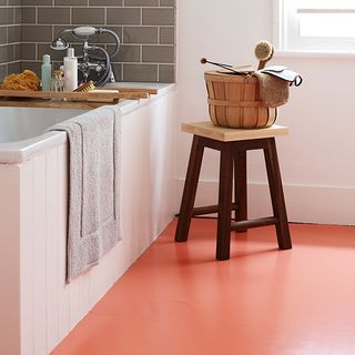 bathroom with orange floor and stool with towel