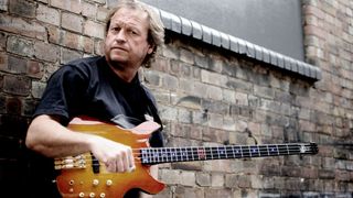 Level 42's Mark King leaning against a wall with his bass