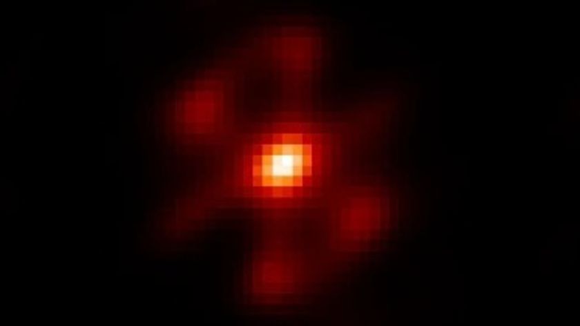 A pixelated image showing a white dot surrounding by orange and red light against a black background