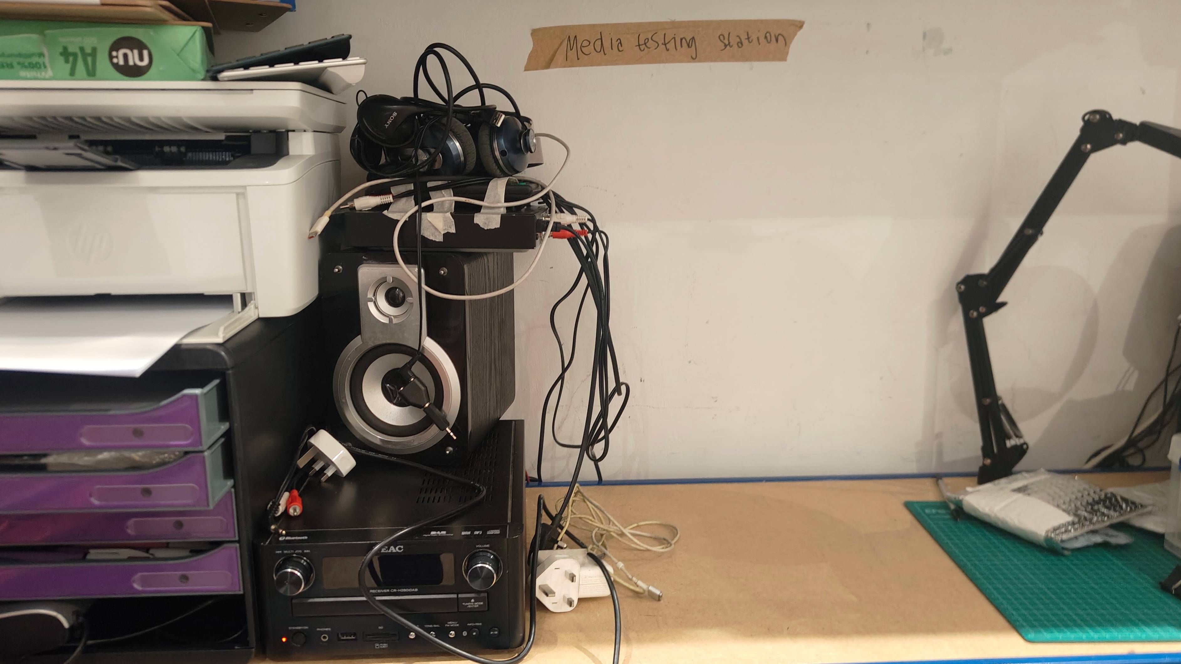 Some broken speakers and radio, with a sign saying "Media testing station".