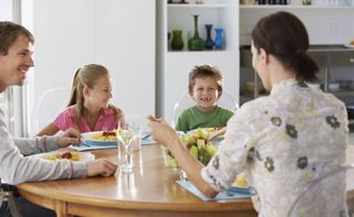 Mother and father sharing a meal with with boy and girl at kitchen table. 