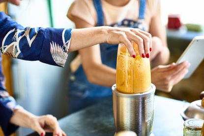 woman making a smoothie in a blender