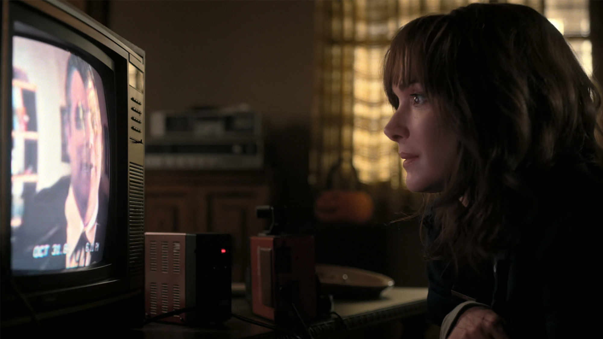 Winona Ryder looking closely at a TV in Stranger Things