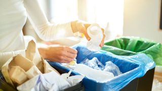 Close up view of hands of young woman sorting garbage in kitchen