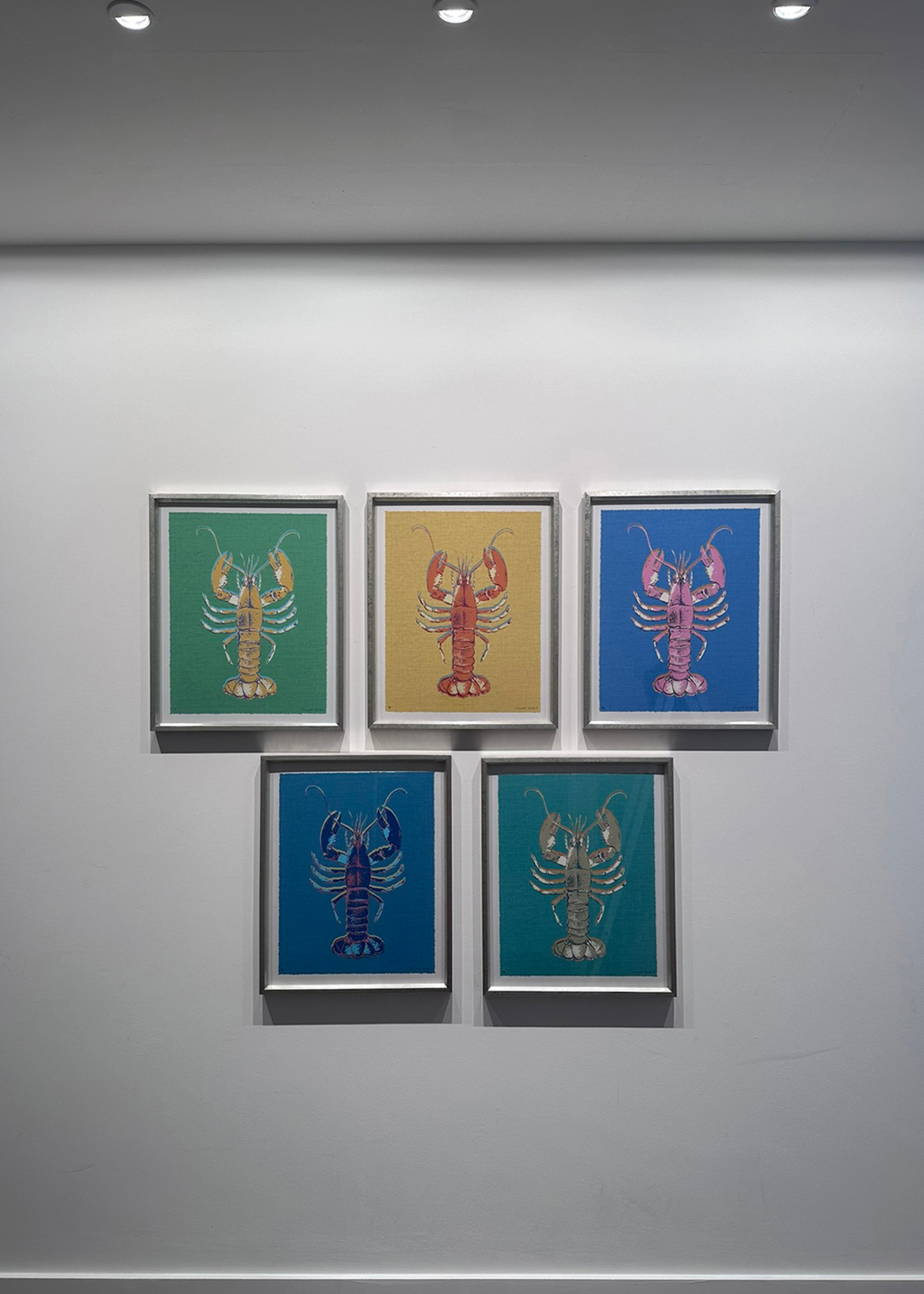 five lobster paintings on a wall with wall washing lights