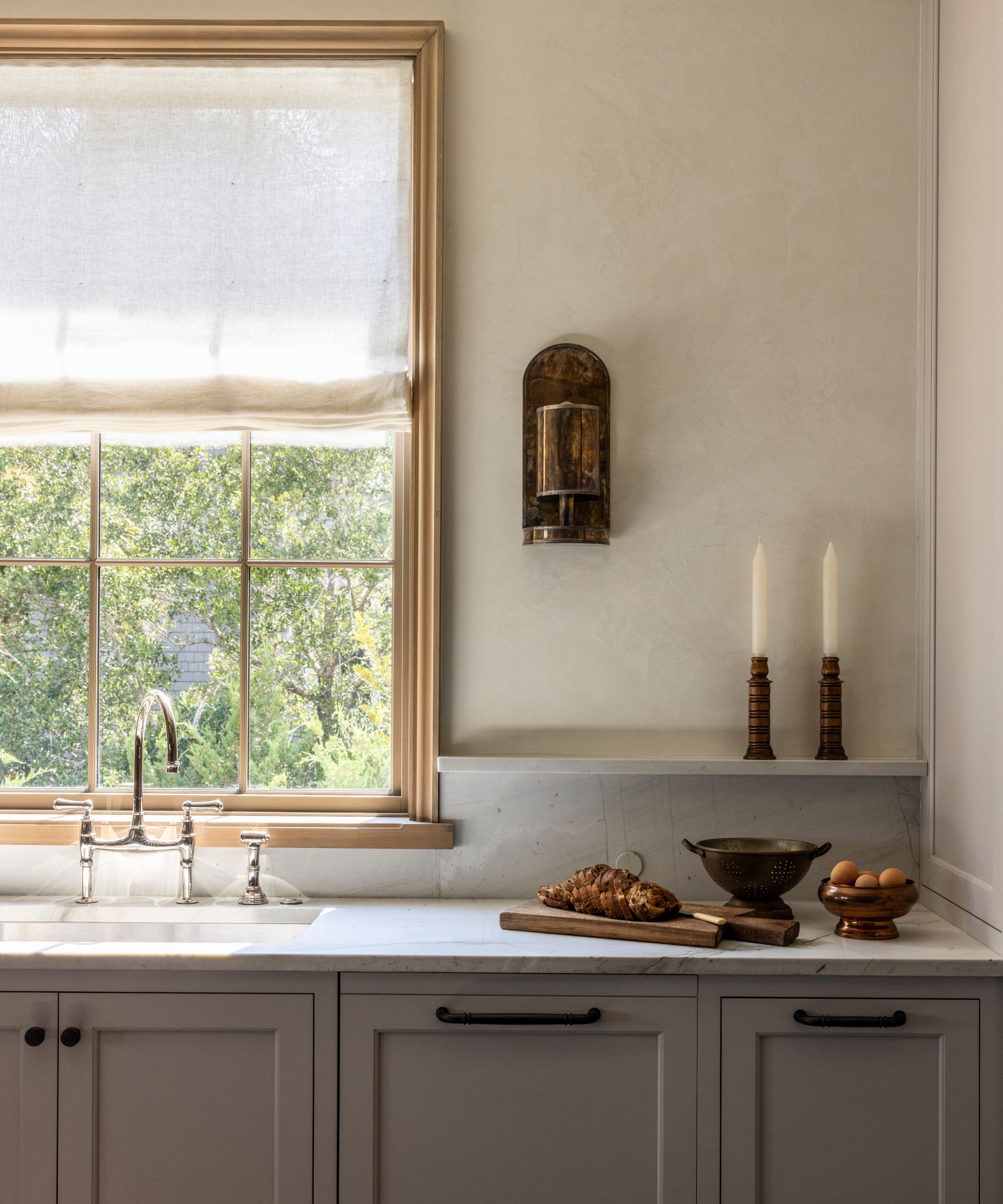A small kitchen with deep taupe cabinets, marble countertops, and a arm white textured wall paint