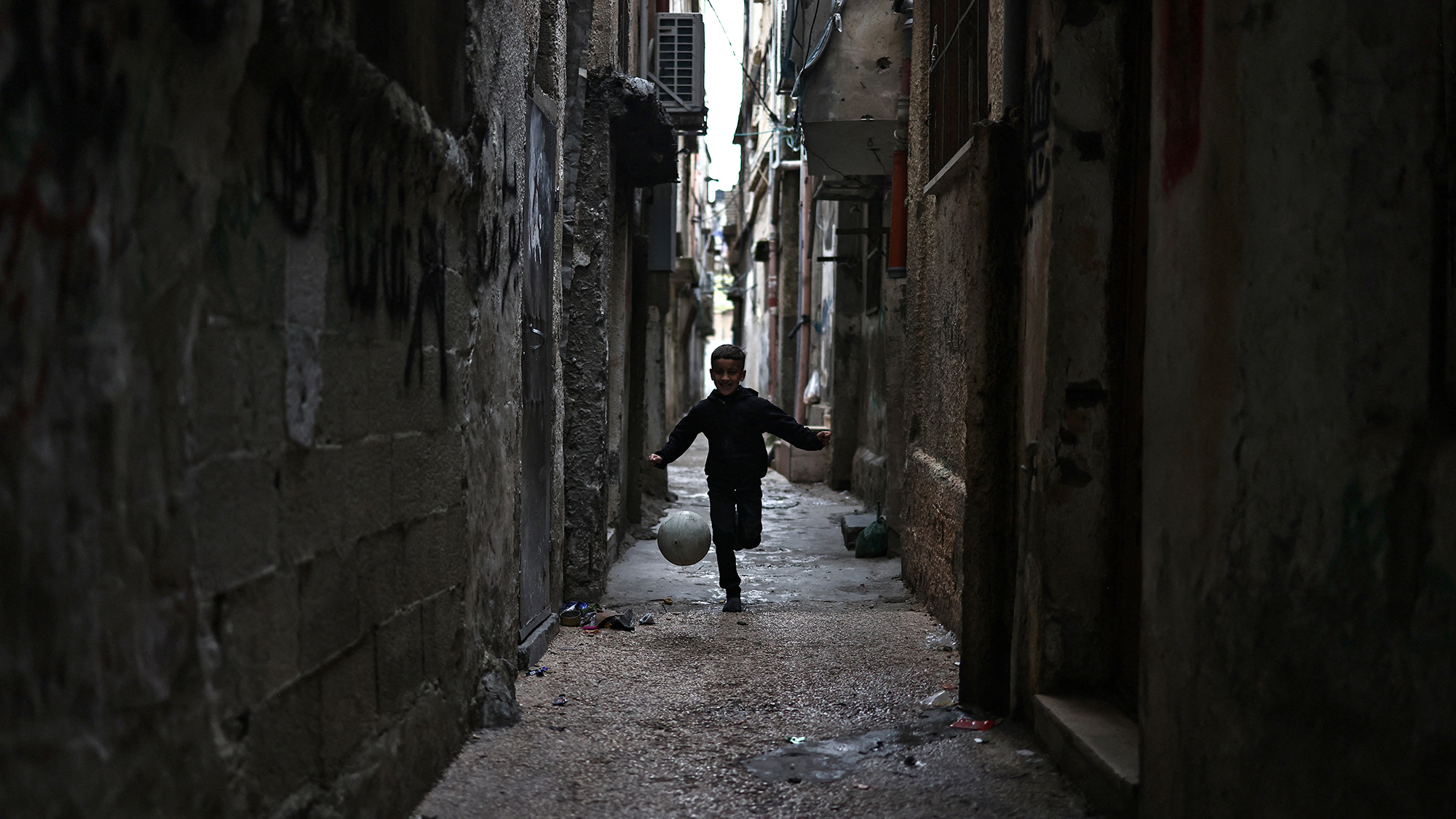 A boy kicks a ball down an alley near the Balata camp for Palestinian refugees in the occupied West Bank
