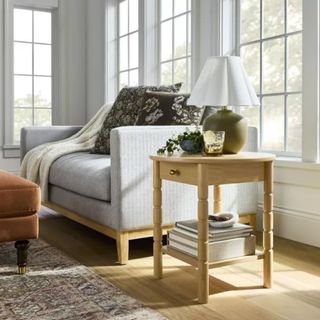 A gray sofa and a wooden side table with green and white table lamp