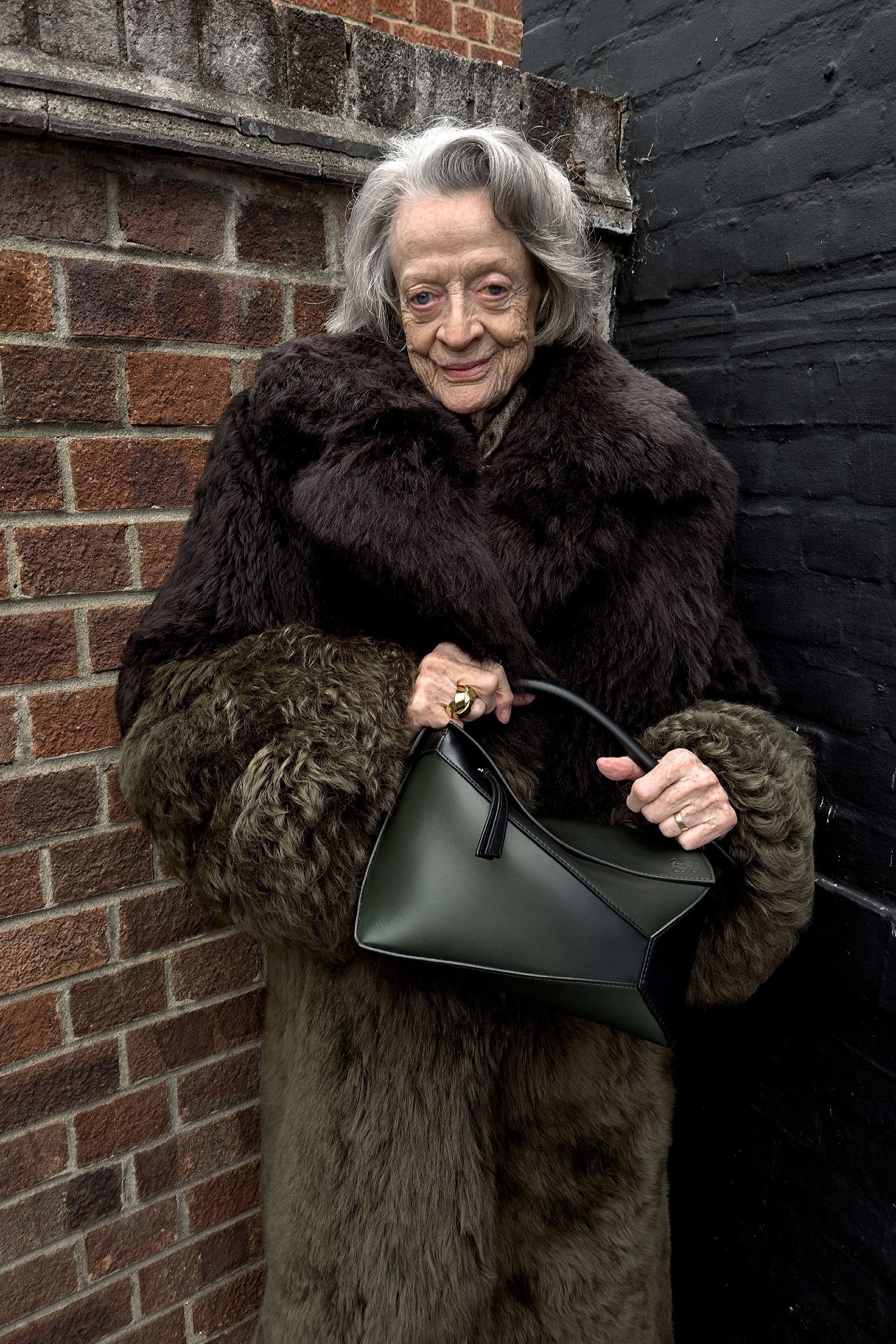 An image of Dame Maggie Smith wearing the Loewe Puzzle bag as part of the brand's spring 2024 pre-collection.