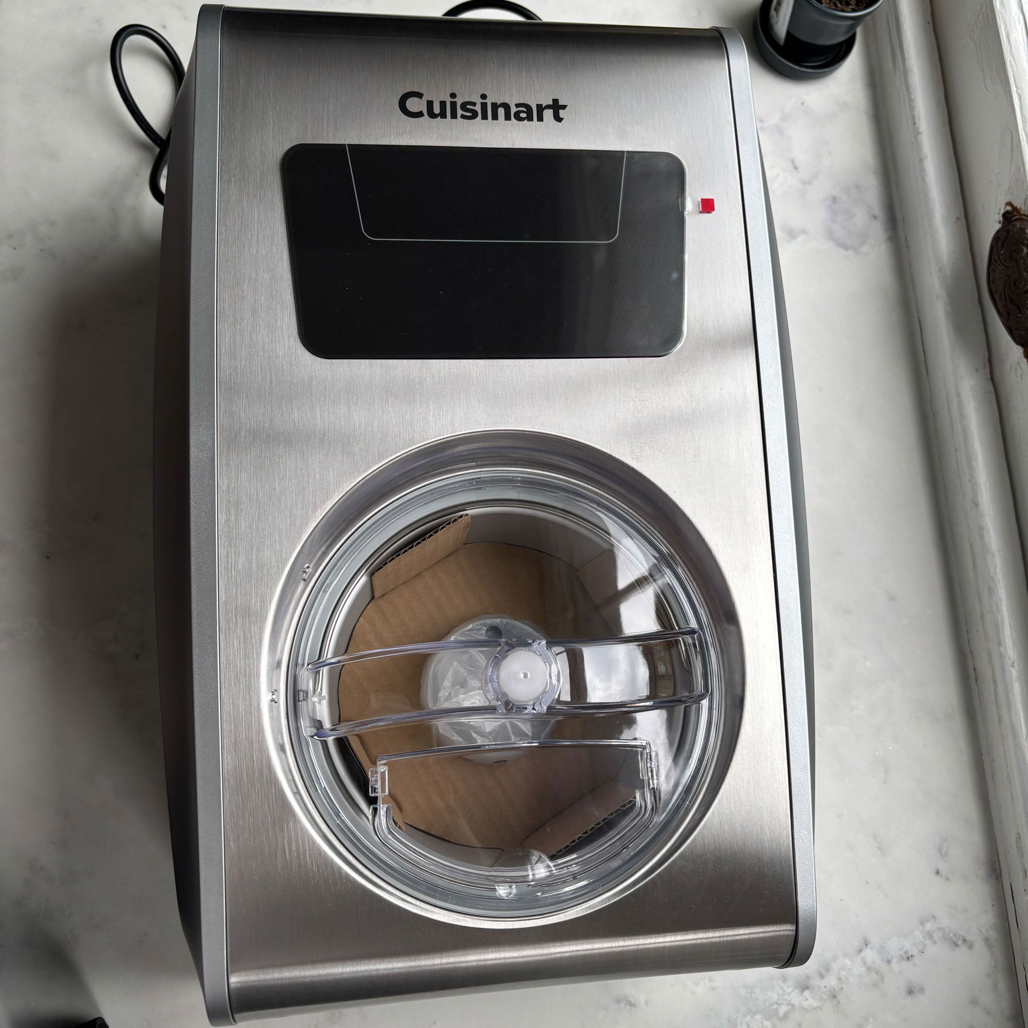 Stainless steel Cuisinart ice cream maker on top of a white kitchen countertop