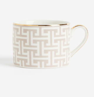 tea cup with beige pattern and gold rim and handle