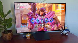 LG UltraGear 32GS95UE-B monitor on desk with Pharah from Overwatch 2 character select on screen