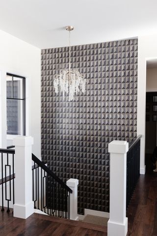 Grey stairwell with glass chandelier and bold feature gray geometric wallpaper