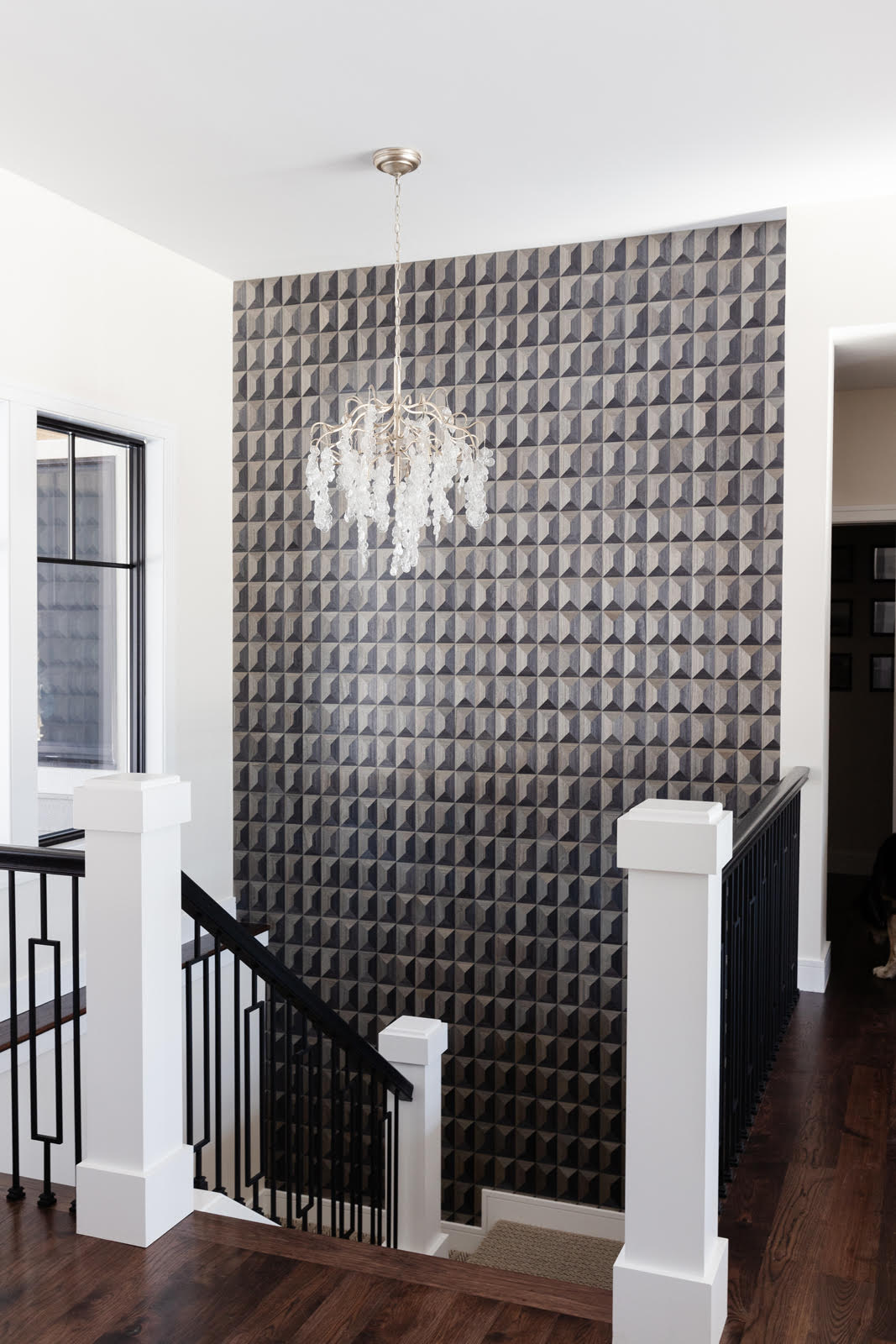 Grey stairwell with glass chandelier and bold feature gray geometric wallpaper