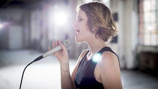 Woman sings into a microphone