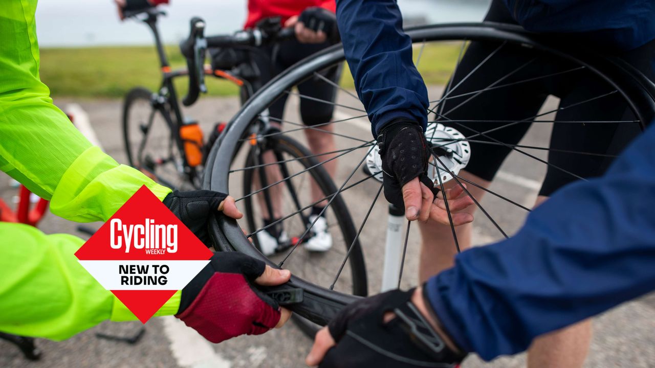 Group of cyclists work together to get a tyre back on the rim