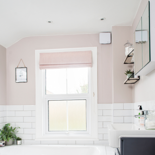 a pink and white bathroom with white square extractor fan by window