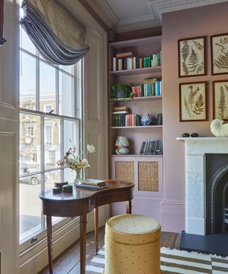 pink living room with a large window and a marble fireplace designed to have a small vintage deck and yellow upholstered stool