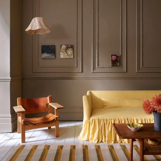 Grey green living room wall with period-style panelling and white painted floorboards