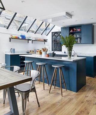 Open plan kitchen diner with blue cabinetry and wood flooring