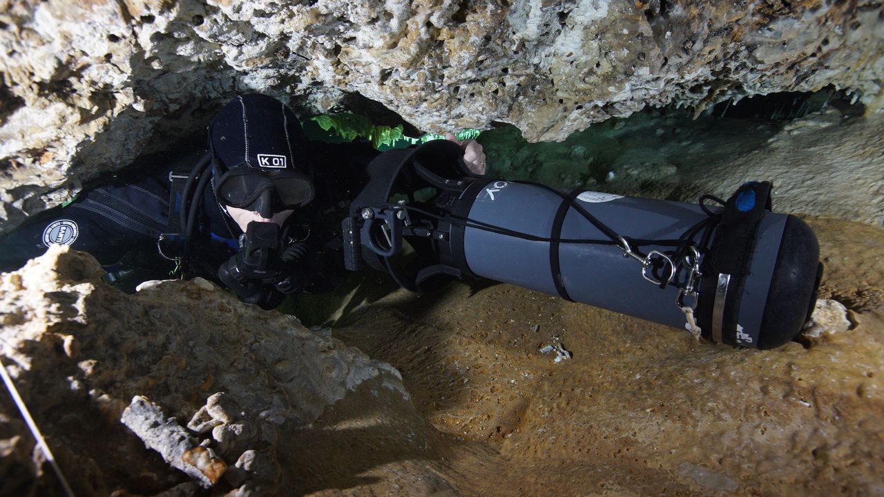 A CINDAQ diver squeezes through a narrow passageway in the cave.