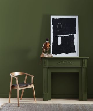 dark green wall with fireplace with wooden armchair, black and white abstract artwork