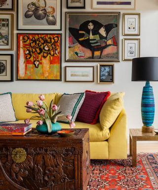yellow sofa and gallery wall with antique chest and rug