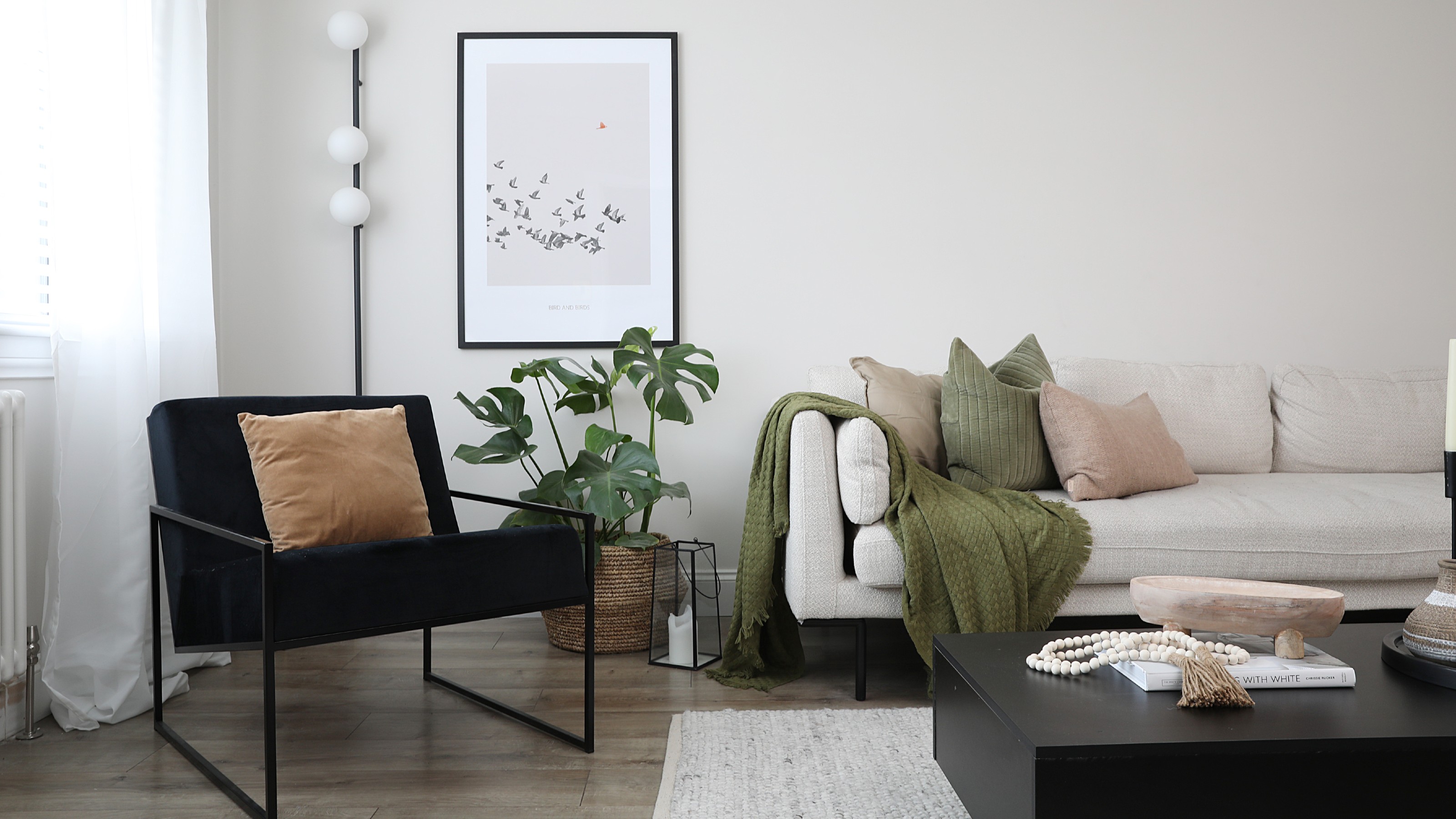 An off-white living room with a beige sofa, a black accent chair and a matching coffee table