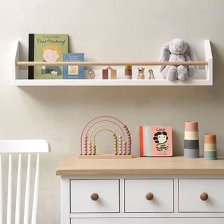 A white wooden bookshelf styled with various childrens toys